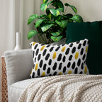 Decorative pillow with black and yellow polka dot pattern on a couch with a plant in the background.