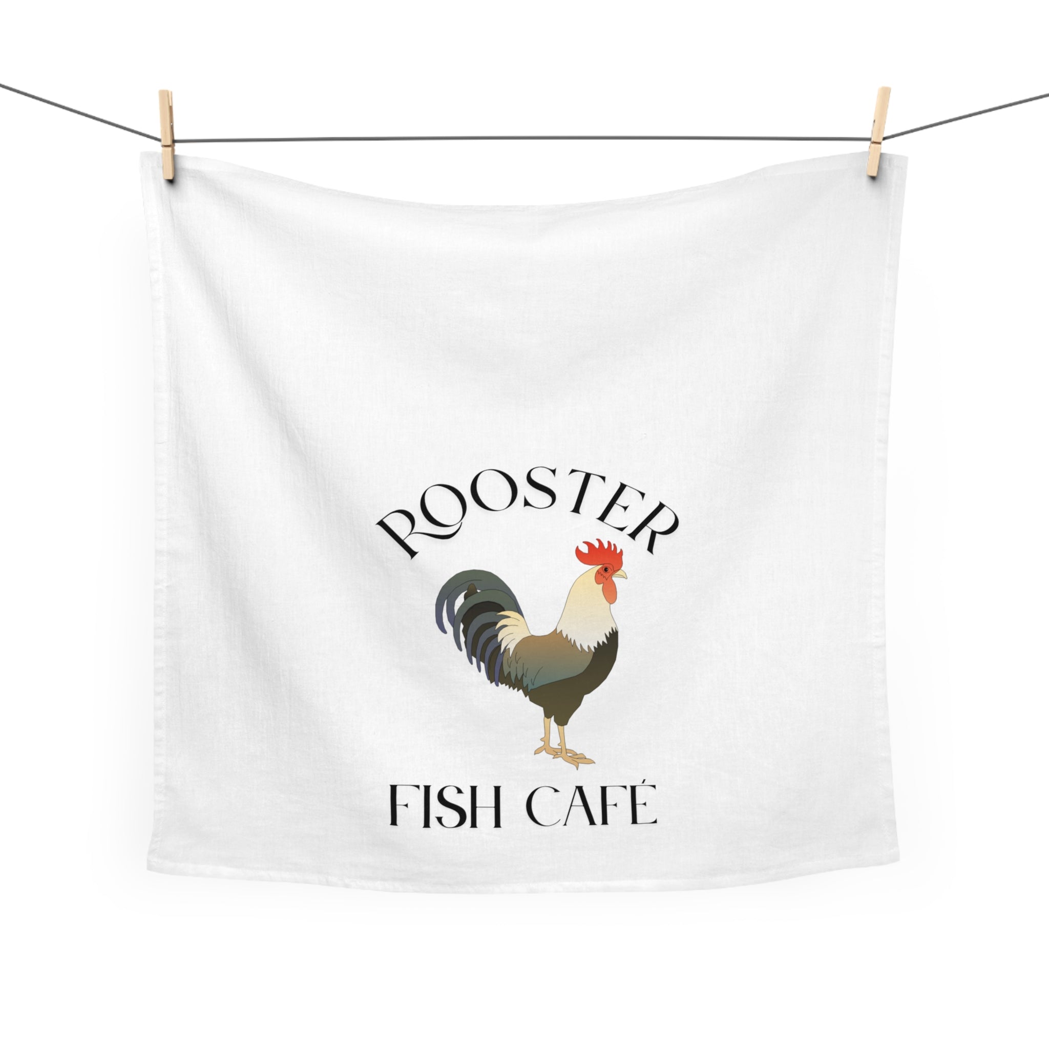 White towel with rooster graphic and 'Rooster Fish Cafe' text hanging on a line.