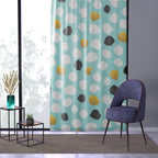 Polka dot curtain with a blue chair and small tables in a room.