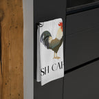 Tea towel with a rooster design and 'SH CA' text hanging on a black cabinet.