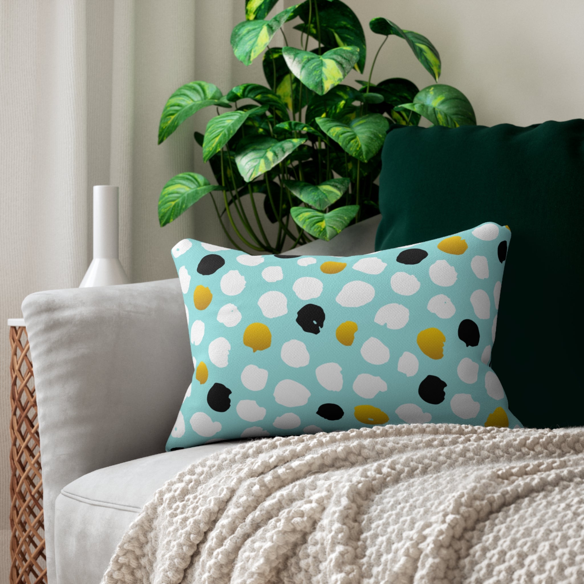 Polka dot pillow on a couch with a plant in the background